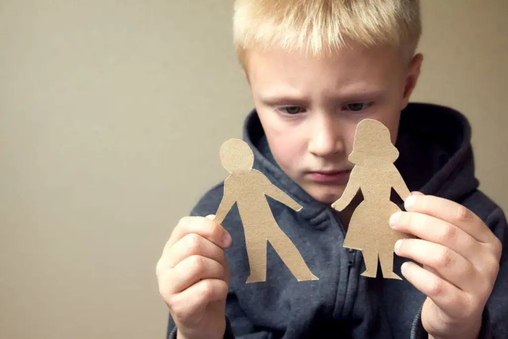 Younger boy holding paper cutouts in the shape of a man and a woman