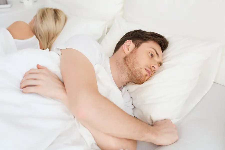 Couple lying back to back, man unable to sleep